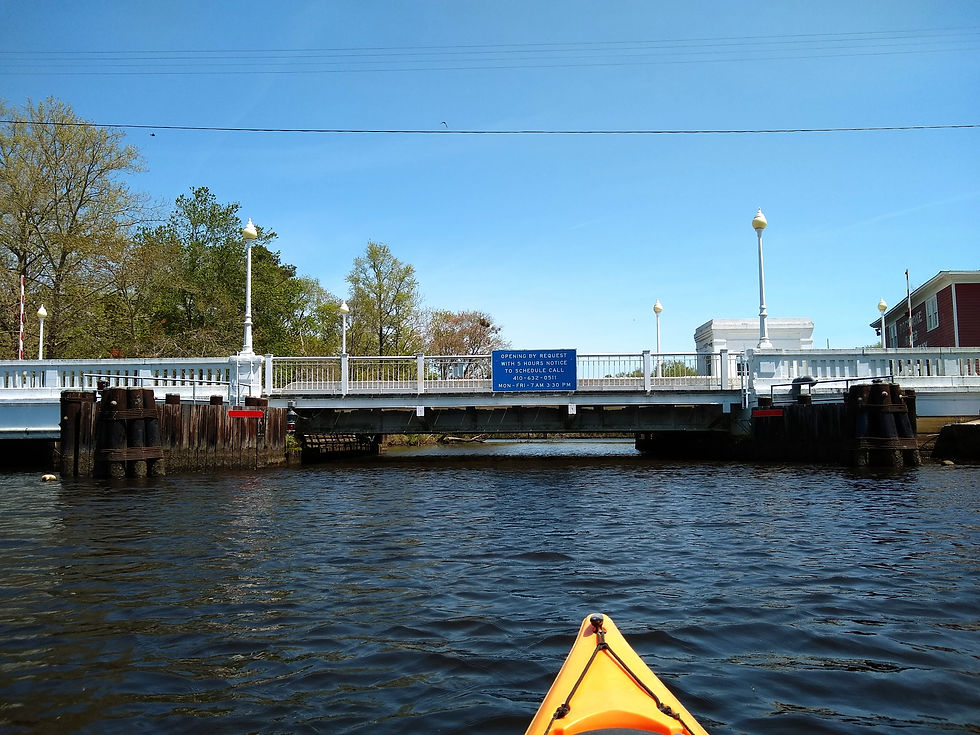 a low drawbridge is closed across a waterway as a kayak attempts to go underneathe