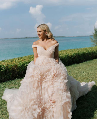 Blonde haired bride in a blush belled gown. Center-part with wave and natural makeup. Photo taken in front of the ocean at the Four seasons Ocean Club resort