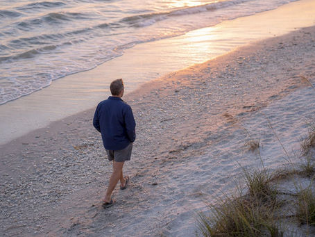 Man walking on beach at sunset golden hour