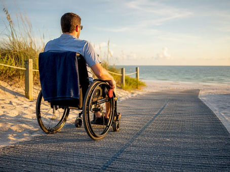 Wheelchair user crossing beach access mat