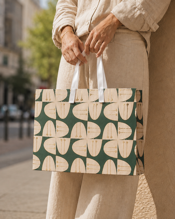 Person holding a patterned green and beige shopping bag.
