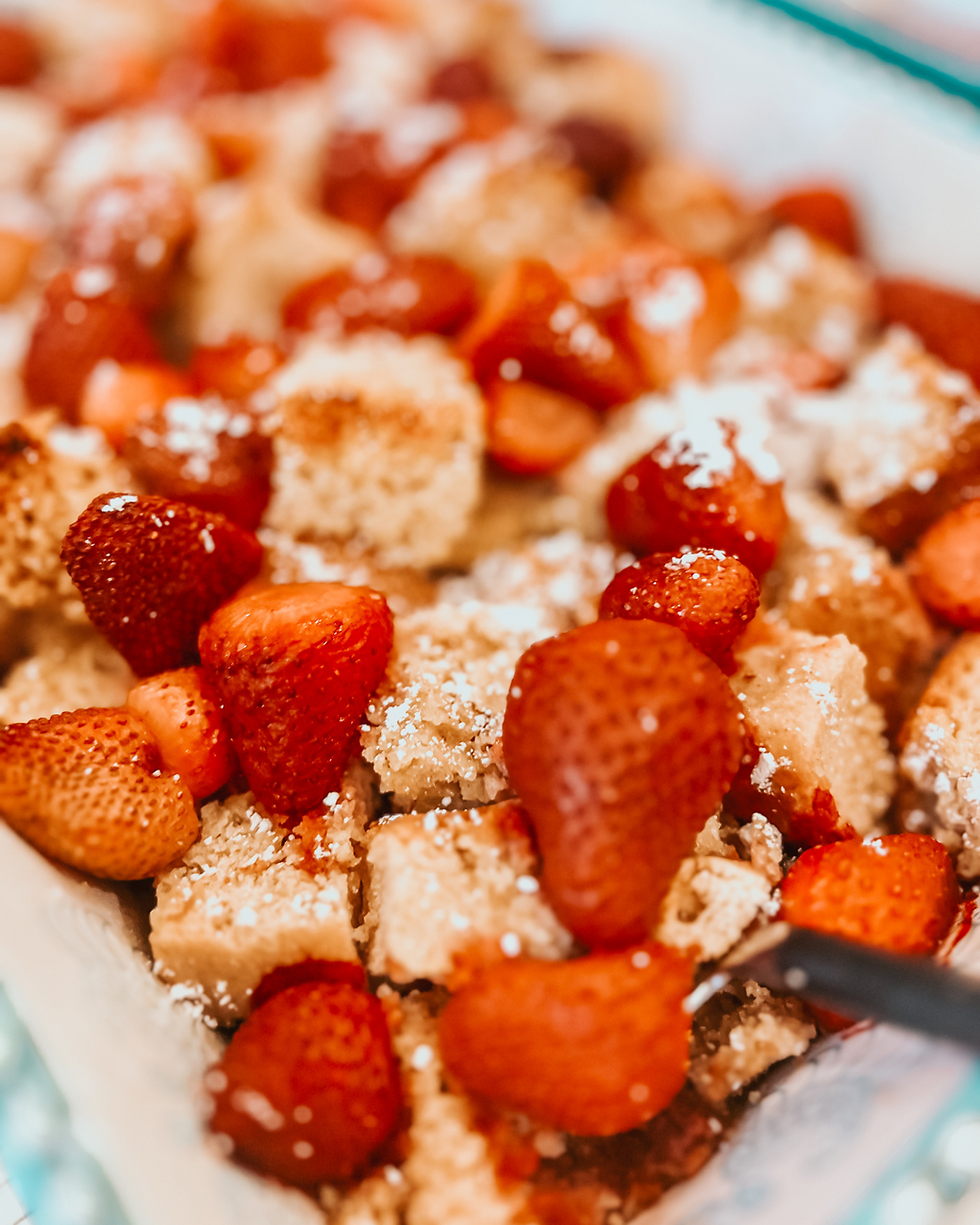 Strawberries and sponge cake pieces dusted with powdered sugar fill a dish. The setting is bright, creating a fresh, delicious appeal. french toast bake, make ahead breakfast, holiday brunch casserole, overnight french toast, easy christmas breakfast, thanksgiving brunch recipe, berry french toast, cinnamon french toast, cozy breakfast ideas, hosting brunch recipes