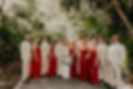 Bridal party with groomsmen wearing beige linen suits and bridesmaids wearing red dresses at a Dreams Sapphire wedding in Mexico.