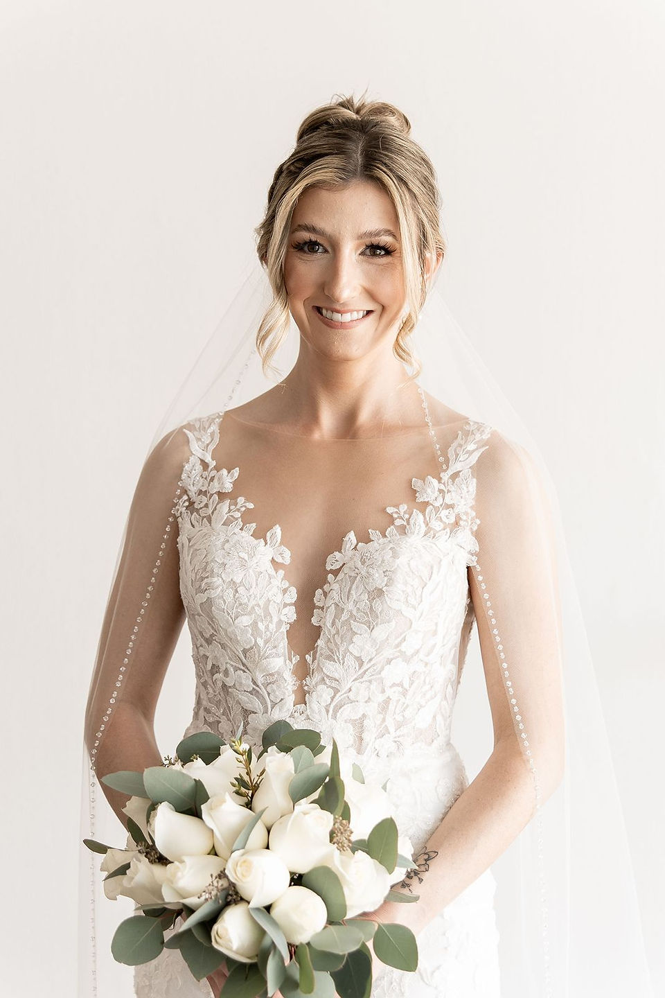 Beautiful bride with hair up holding white bouquet.