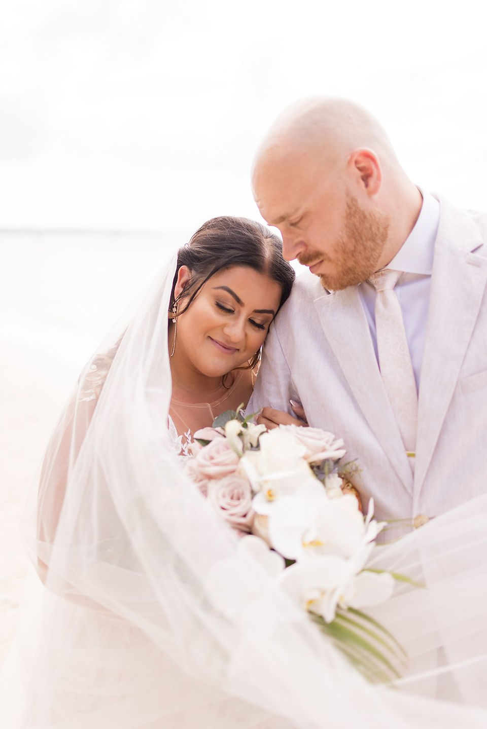 Bride holding her wedding bouquet leaning her head on the groom's shoulder.
