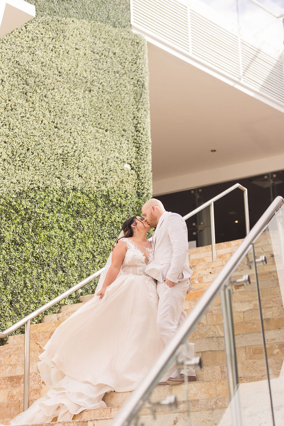 Bride and groom kissing on the stairs up to the sky wedding terrace venue at the all-inclusive Azul Negril resort in Jamaica.