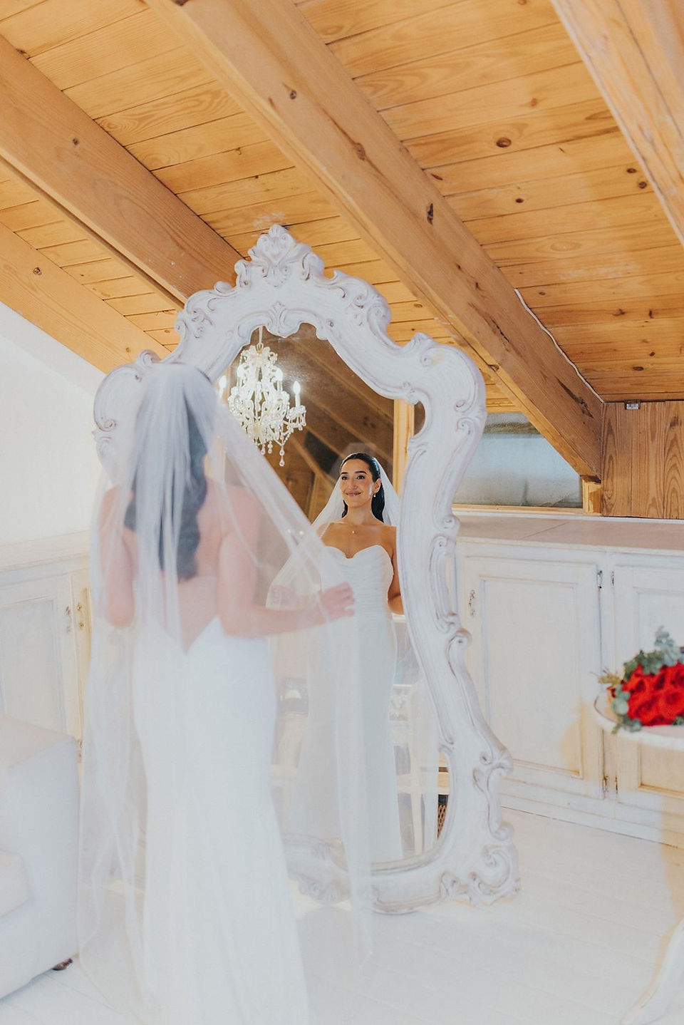 Bride looking at herself in front of antique mirror.