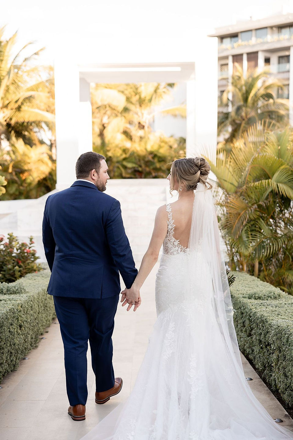 Bride and groom walking away holding hands.