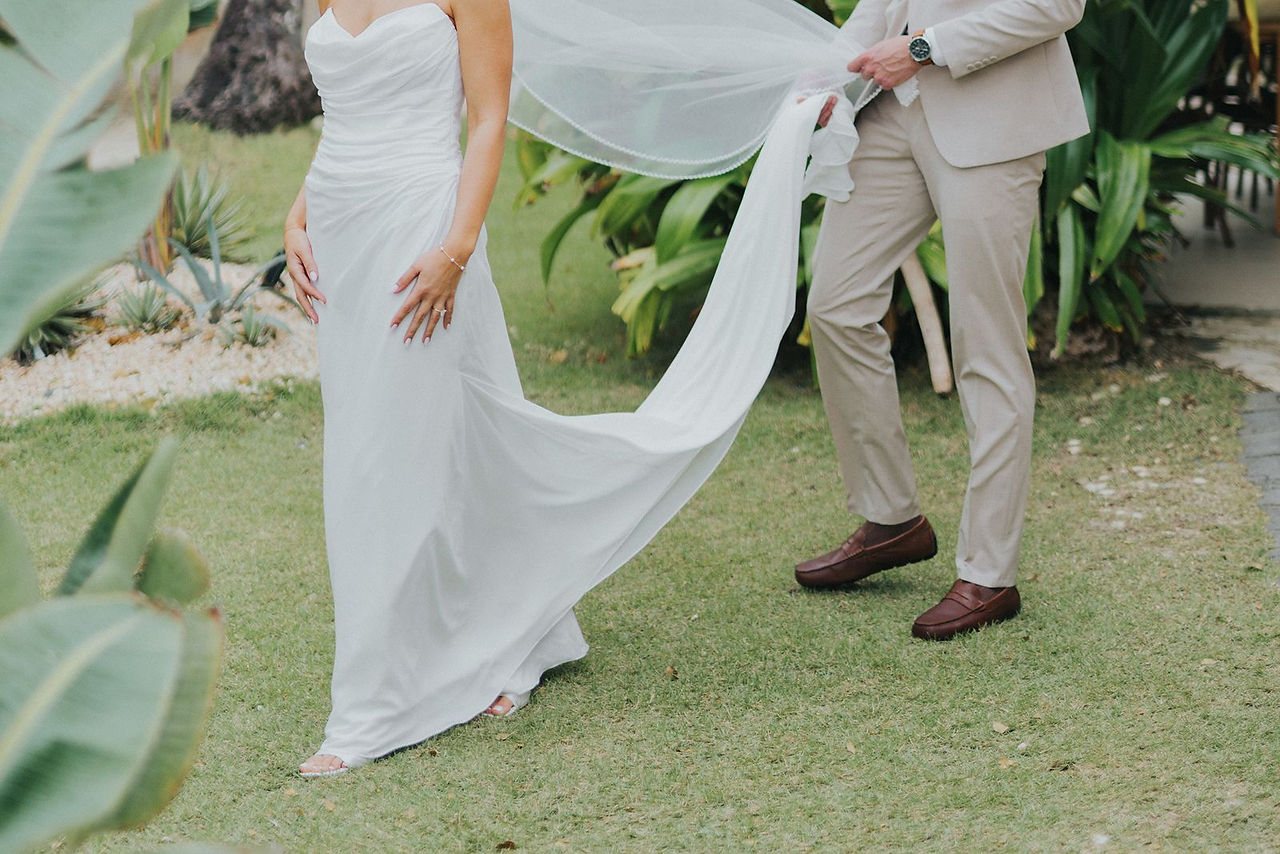 Groom carrying his bride's wedding dress train.