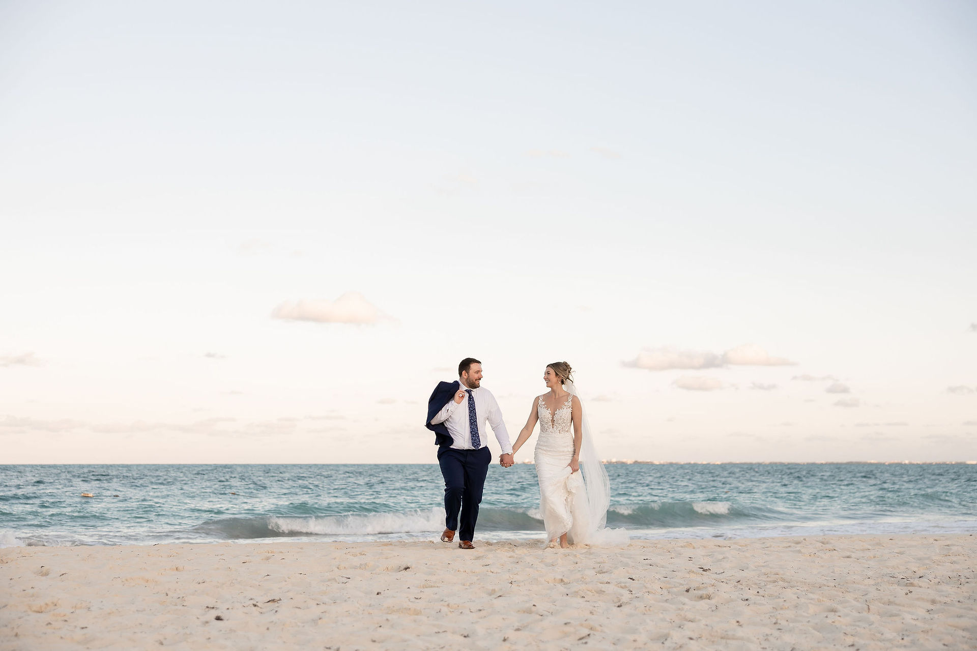 Mexico destination wedding couple walking on the beach holding hands.