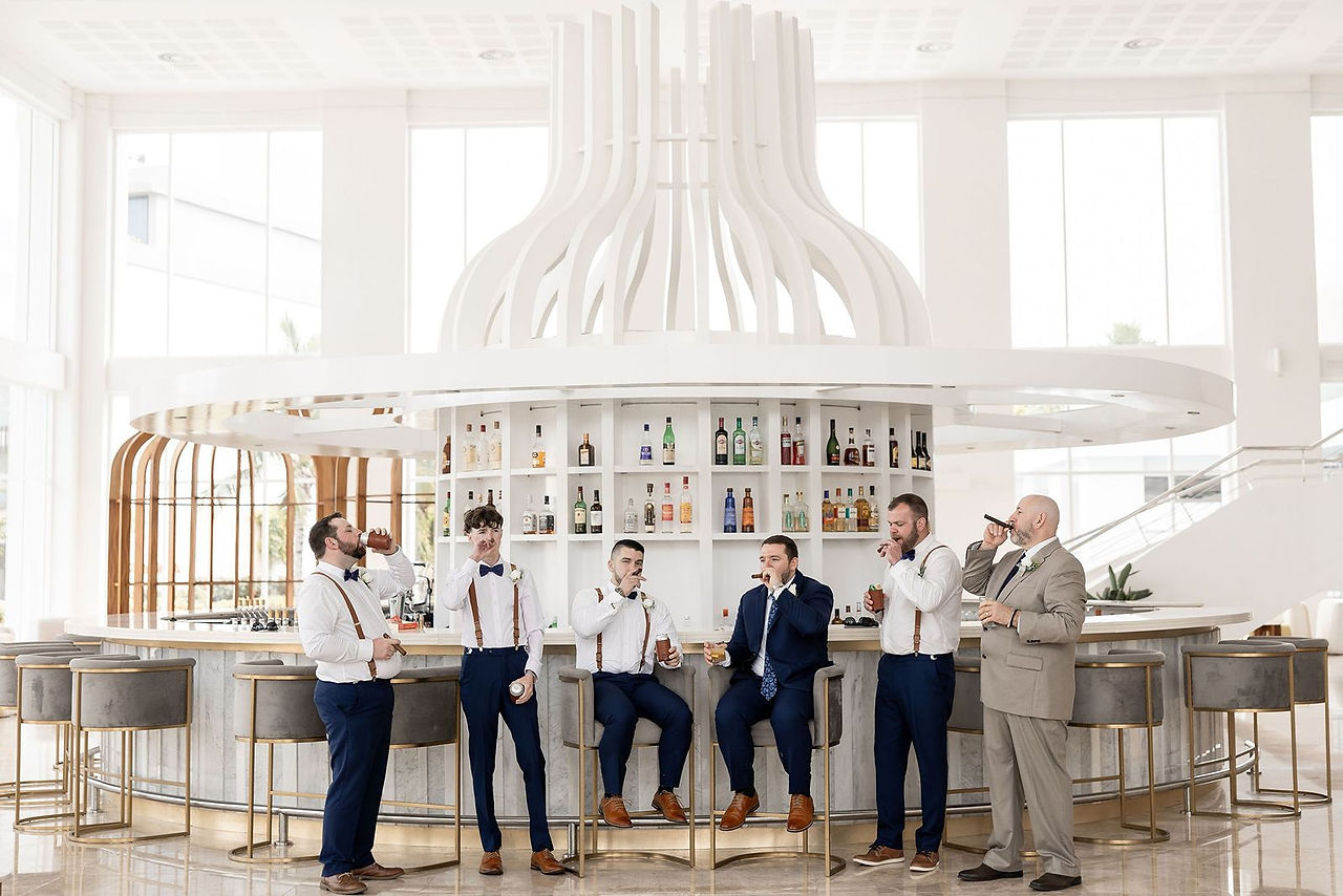 Groomsmen enjoying a cigar and cocktail with groom at lower lobby bar at Majestic Elegance Costa Mujeres resort.