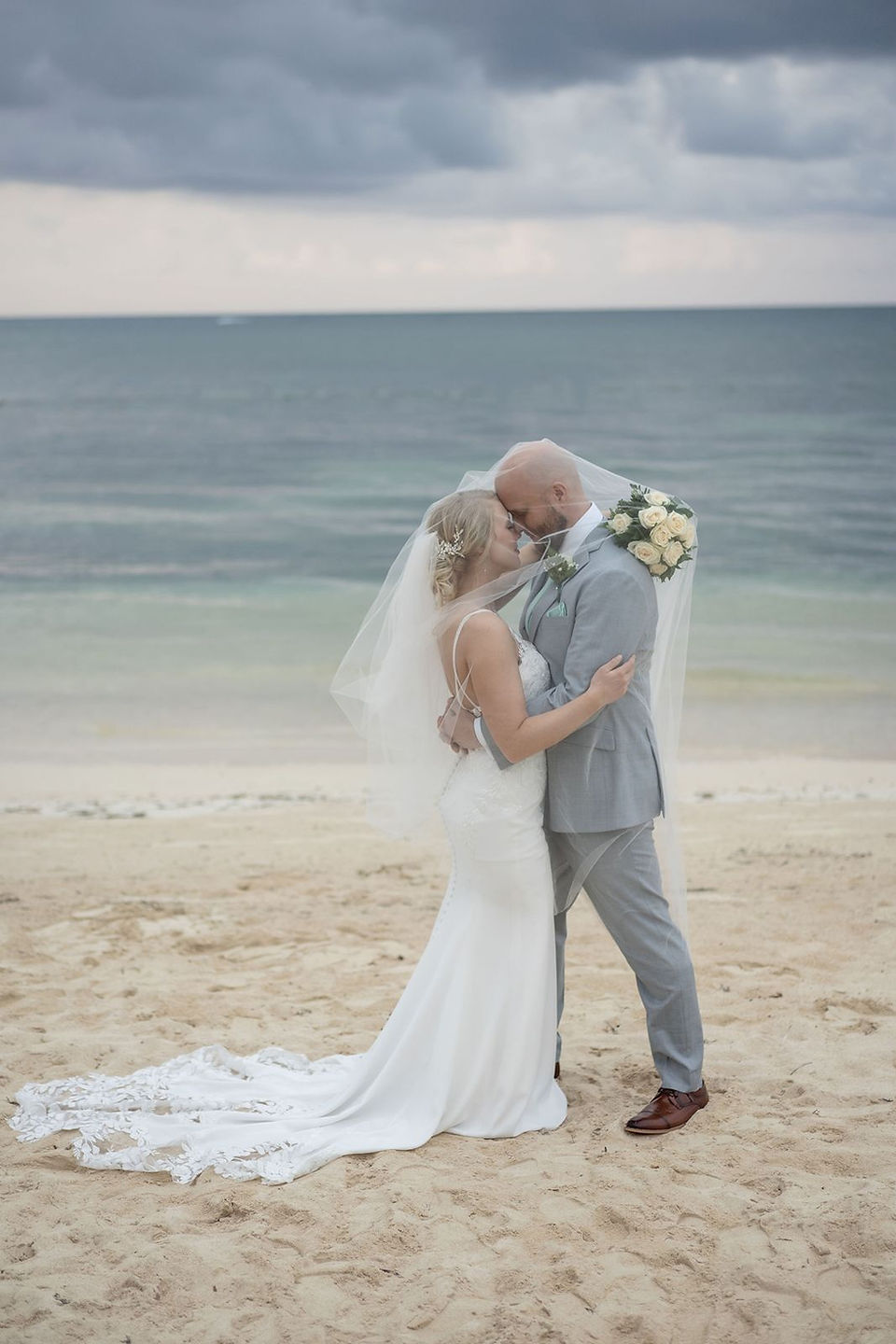 Bride and groom embracing on beach at their JOIA Rose Hall wedding in Jamaica.