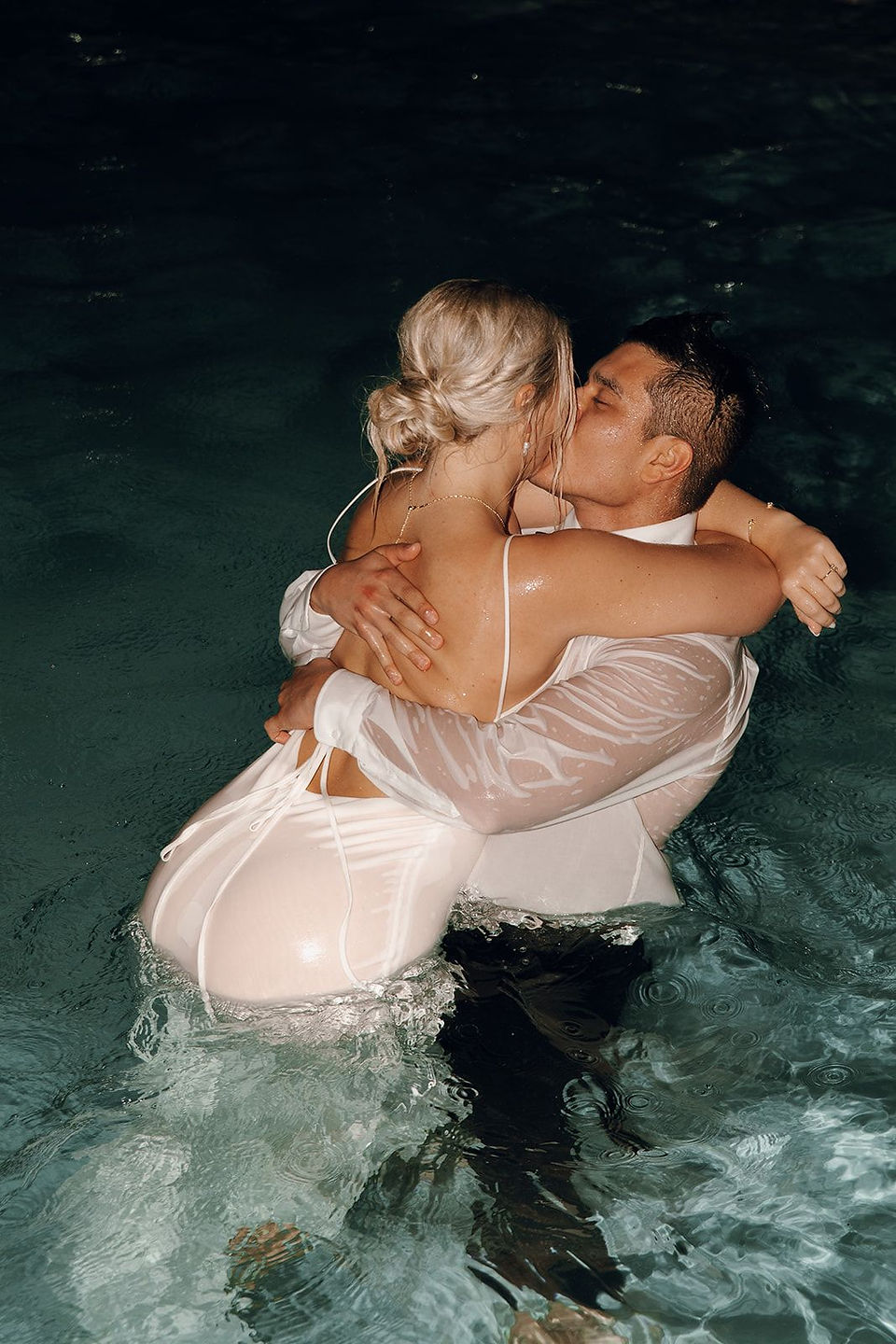 Bride and groom kissing in the pool during their trash the dress moment after their wedding reception at the Dreams Vista wedding resort in Mexico.
