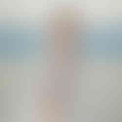 Bride looking over her shoulder holding her pink and white bouquet on the beach in Mexico.