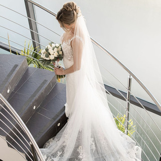 Bride standing on stairs with full length veil.