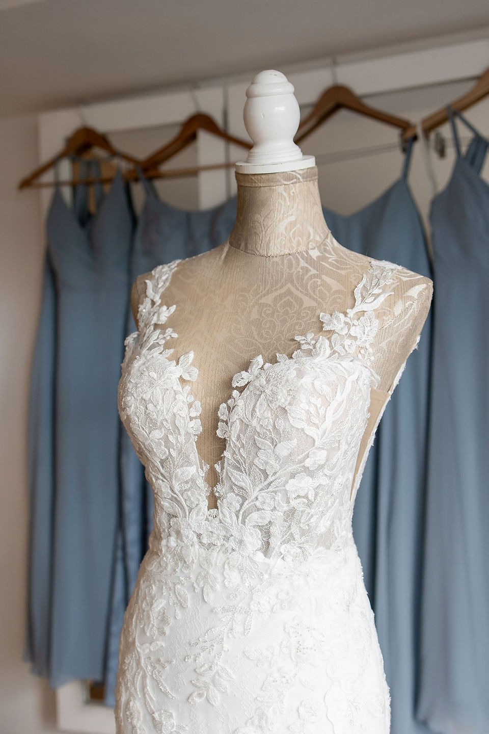Lace white wedding dress in front of dusty blue bridesmaids dresses.