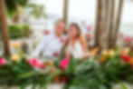Bride and groom at sweetheart table with colorful tropical flowers at the Las Palmas Terrace venue at their Hyatt Ziva Puerto Vallarta wedding in Mexico. 