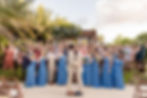 Two grooms kiss amidst cheering guests in front of the wedding gazebo at Unico Riviera Maya in Mexico.