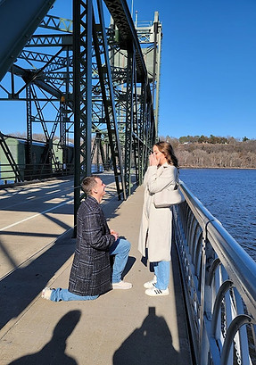 Proposal moment on lift bridge in Stillwater for couple who are planning their destination wedding at Dreams Playa Mujeres in Mexico.