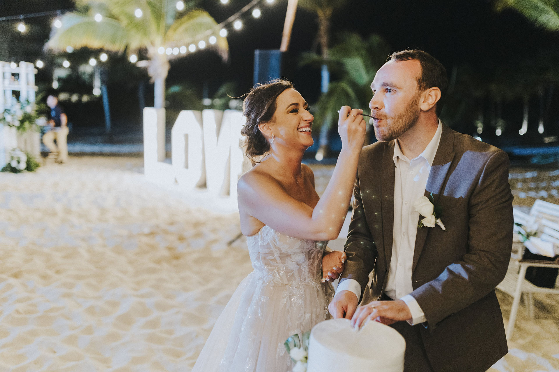 Bride feeding groom cake on the beach at their Majestic Elegance Costa Mujeres wedding resort in Mexico planned by travel agent for destination weddings, EverAfter Travel.