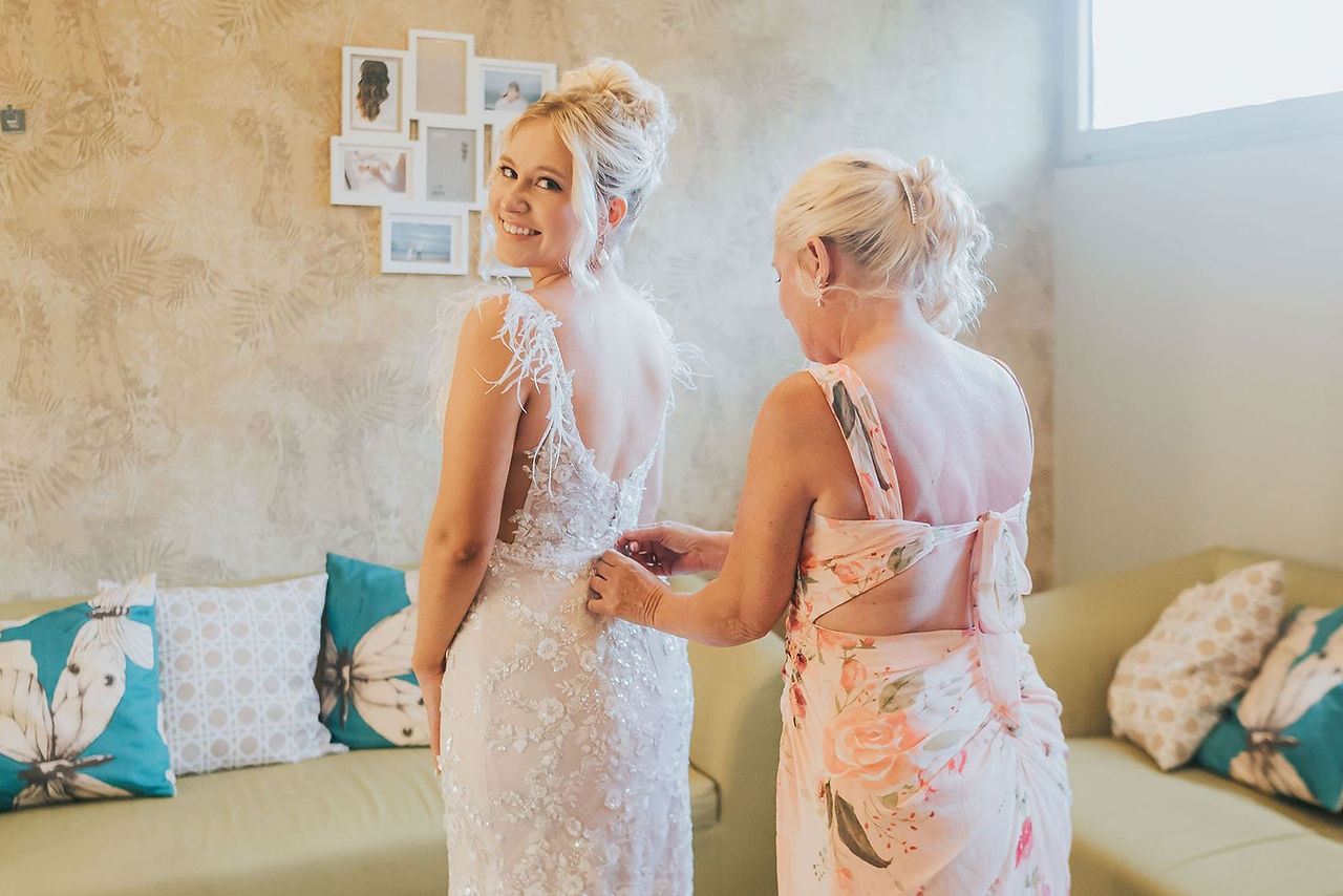 Mother of the bride helping the bride with her dress.