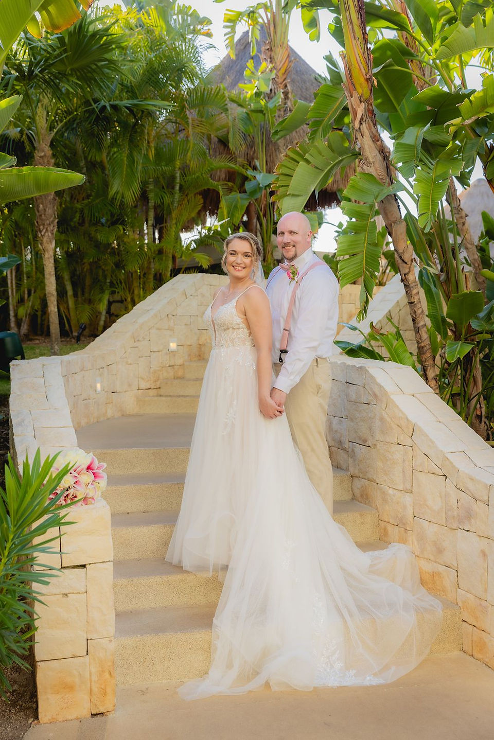 Bride and groom posing on neutral stairway at Dreams Playa Mujeres.