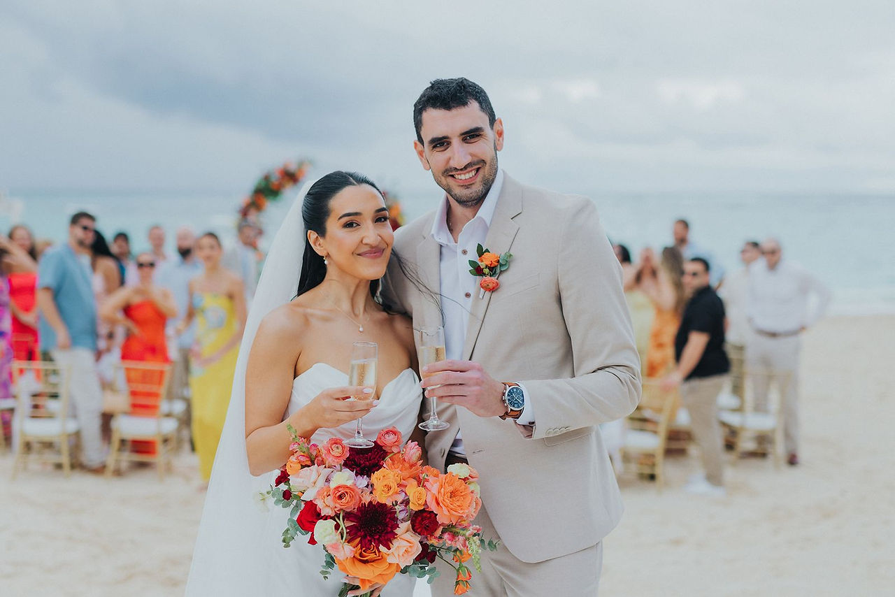 Happy bride and groom with champagne after their beach ceremony.
