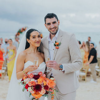 Happy bride and groom with champagne after their beach ceremony.