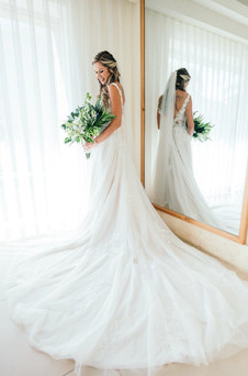 Bride looking at her white tropical bouquet by a window at her Dreams Royal Beach wedding in the Dominican Republic.