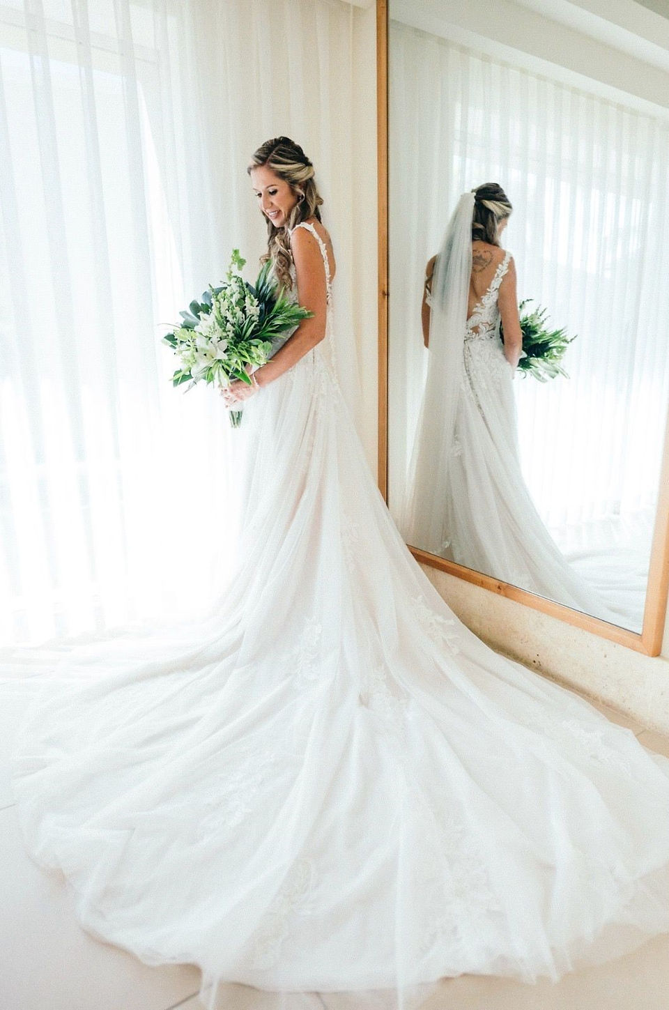 Bride looking at her white tropical bouquet by a window at her Dreams Royal Beach wedding in the Dominican Republic.