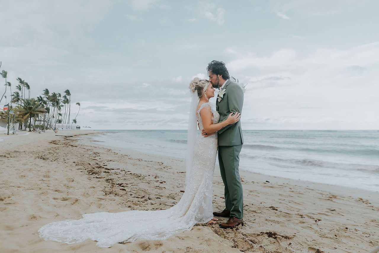 Groom kissing bride's forehead on the beach at Dreams Onyx.