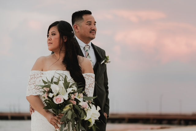 Bride and groom posing at sunset with tropical bouquet at their Dreams Playa Mujeres wedding in Mexico.