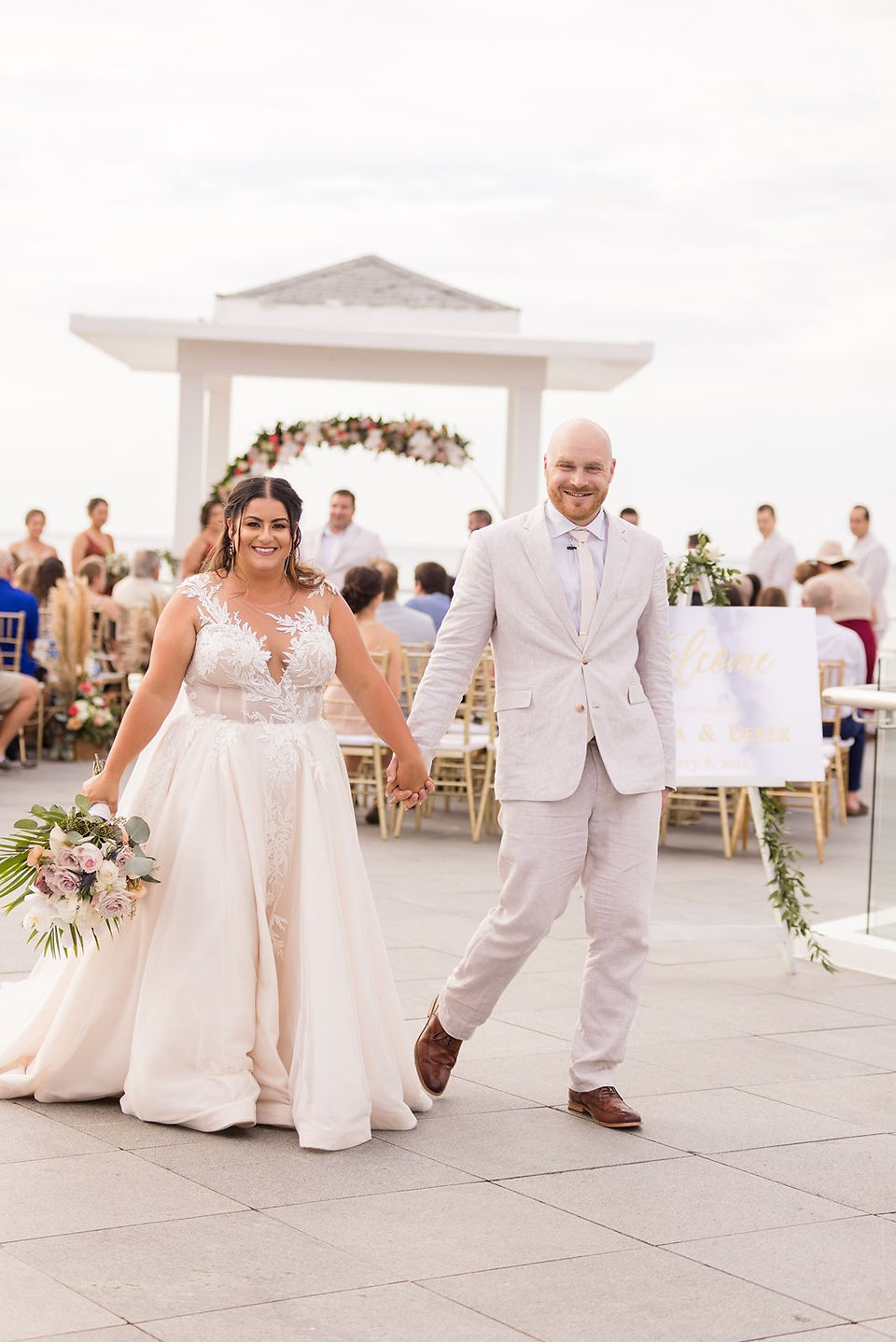 Bride and groom walking away from wedding ceremony with white gazebo at Azul Negril in Jamaica.