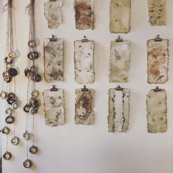 An array of handmade paper stained with railroad rust on one of Mitchell's studio walls