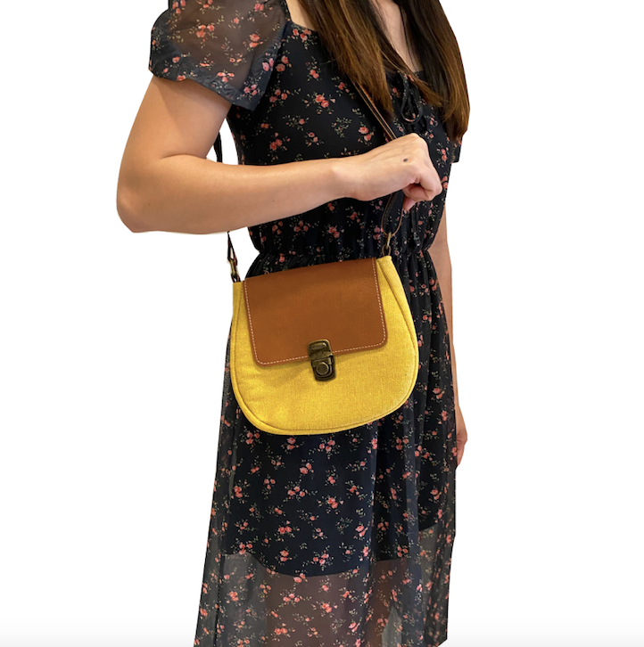 Woman in floral dress with yellow handbag, brown flap. Lightweight Shoulder Handbag: Green Stripes.