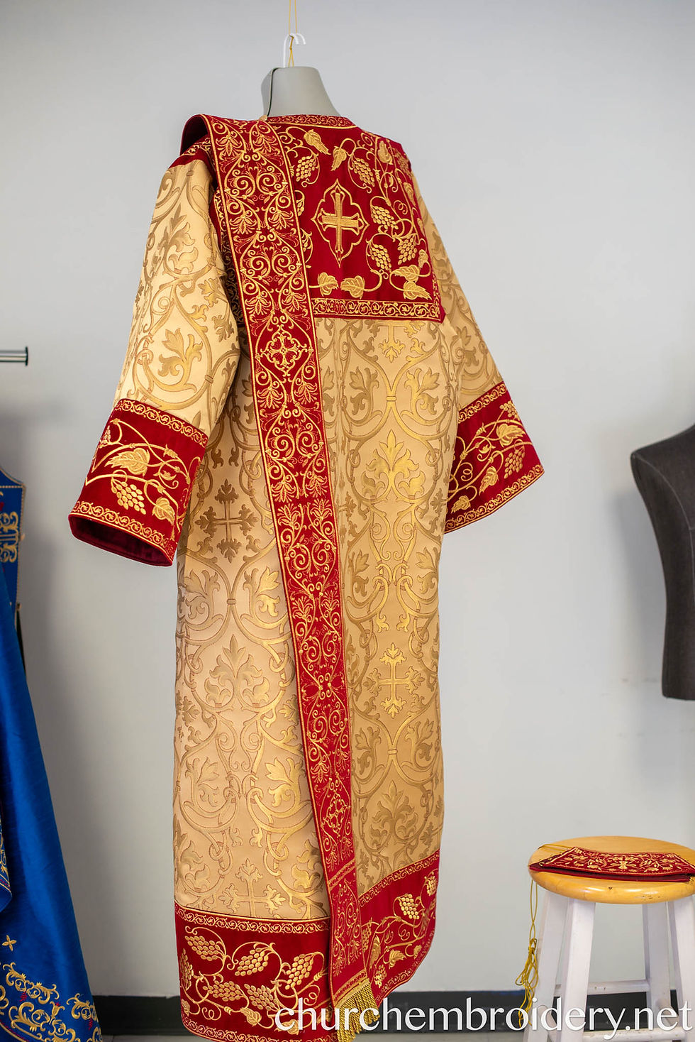 Thumbnail: Rear view: Full-length gold vestment with wide red embroidered panels and cuffs.