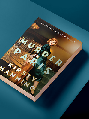 Book titled Murder in Paris by Kirsty Manning on a teal surface. Features a woman in a green dress on the cover, creating a mysterious mood.