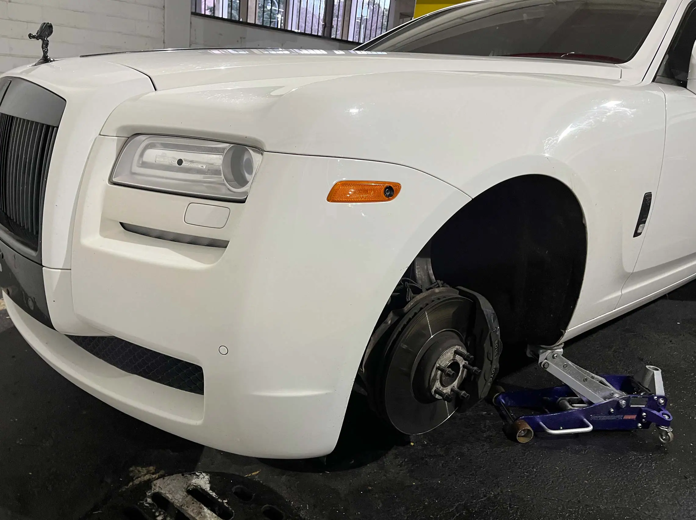 White Bentley on floor jack for tire replacement service