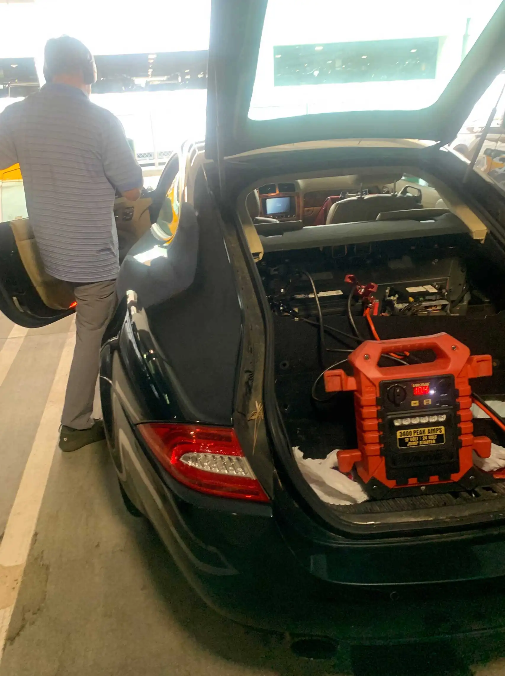 Mobile jump-start service starting vehicle with jumper box at the airport parking.
