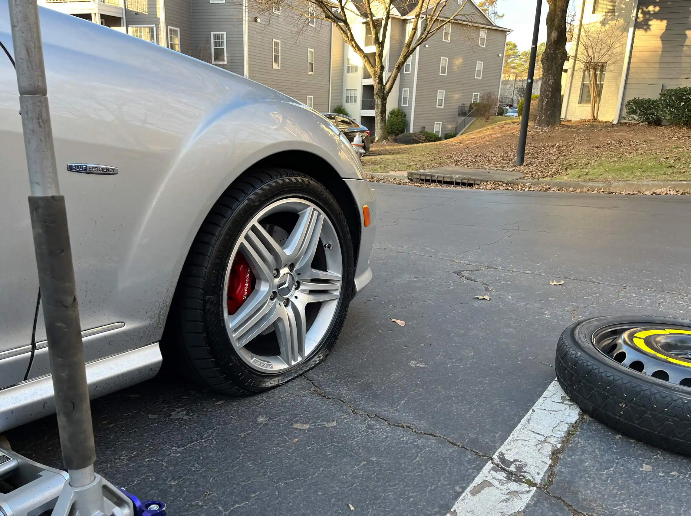 Mobile spare tire change for a flat tire on a gray Mercedes.