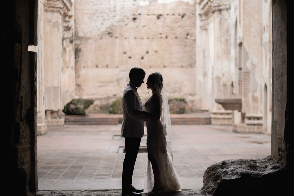 Newlywed couple embraces at Ruinas de Santa Clara, Antigua Guatemala, surrounded by historic beauty.