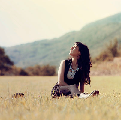 Woman content sitting and being in touch with herself and looking up toward the sun