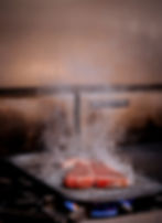 Image of steak being cooked on flat top