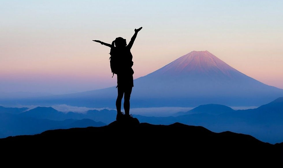 A woman celebrating at the top of a mountain