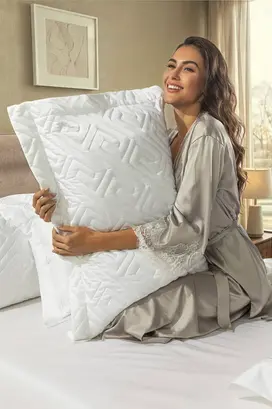 Fotografia comercial de travesseiro produzida para a Lynel, com modelo segurando o produto em ambiente decorado para catálogo, e-commerce e campanhas publicitárias do setor têxtil.