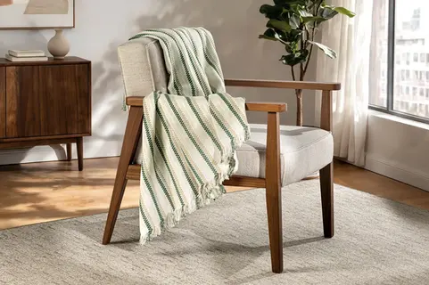 Manta decorativa da marca Vitalícia sobre poltrona em ambiente residencial, em fotografia comercial produzida para o grupo Bella&Co.