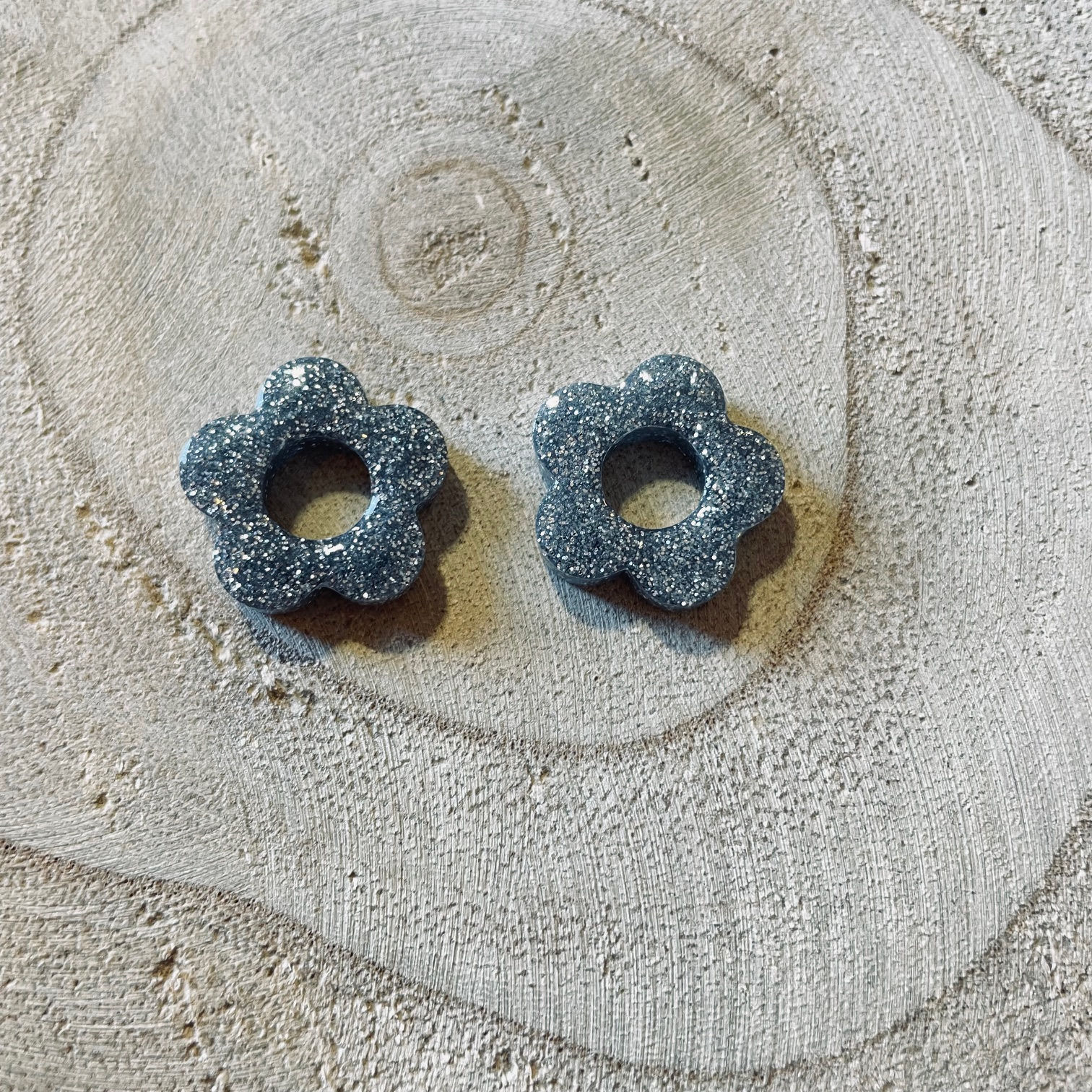 Charmes fleurs en argenté pailleté, posés sur bois.