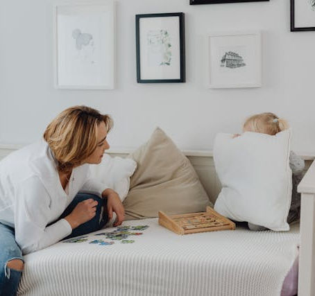 A child hiding behind a pillow while an adult is trying to have a chat