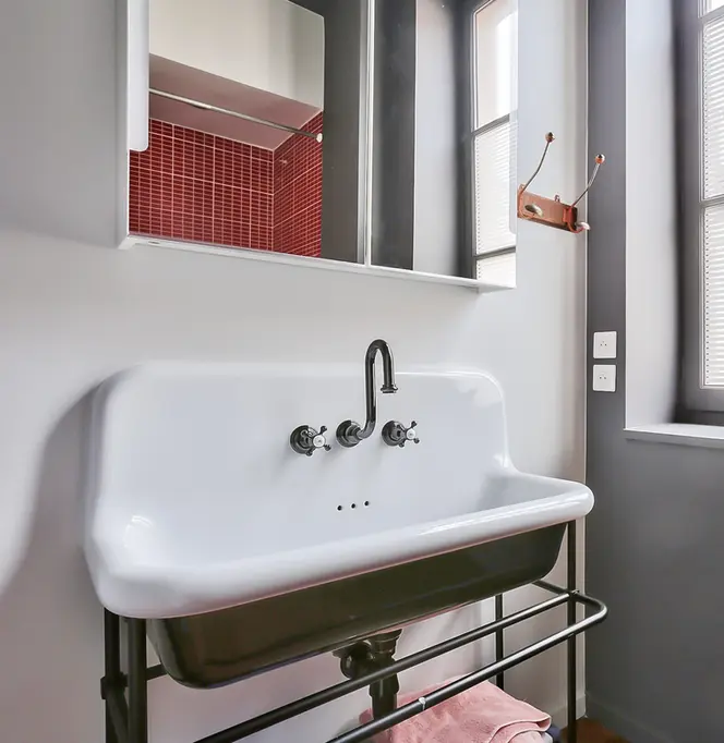 Salle de bain contemporaine avec lavabo industriel blanc et mosaïque rouge dans un appartement rénové à Lyon