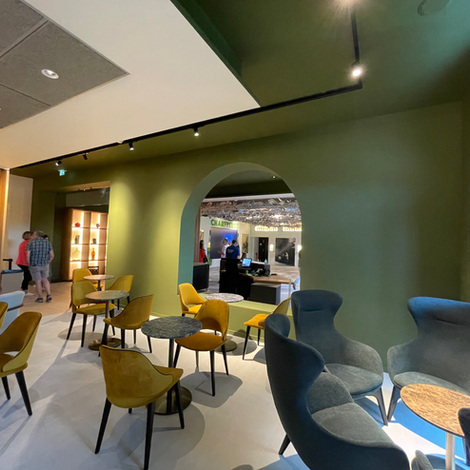 Vue sur l’accueil de La Chartreuse à travers une arche en plein cintre.
Fauteuils doux aux tonalités cuivre et vert, lumière végétale et volumes enveloppants.